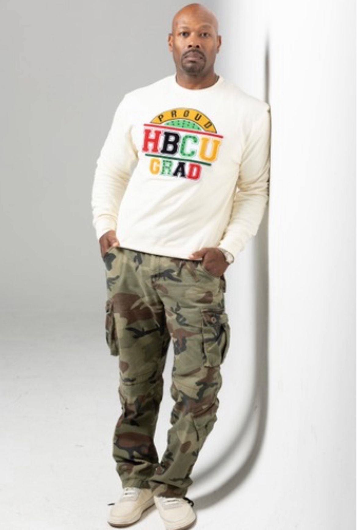 male wearing proud hbcu grad sweatshirt with camo pants on and cream shoes